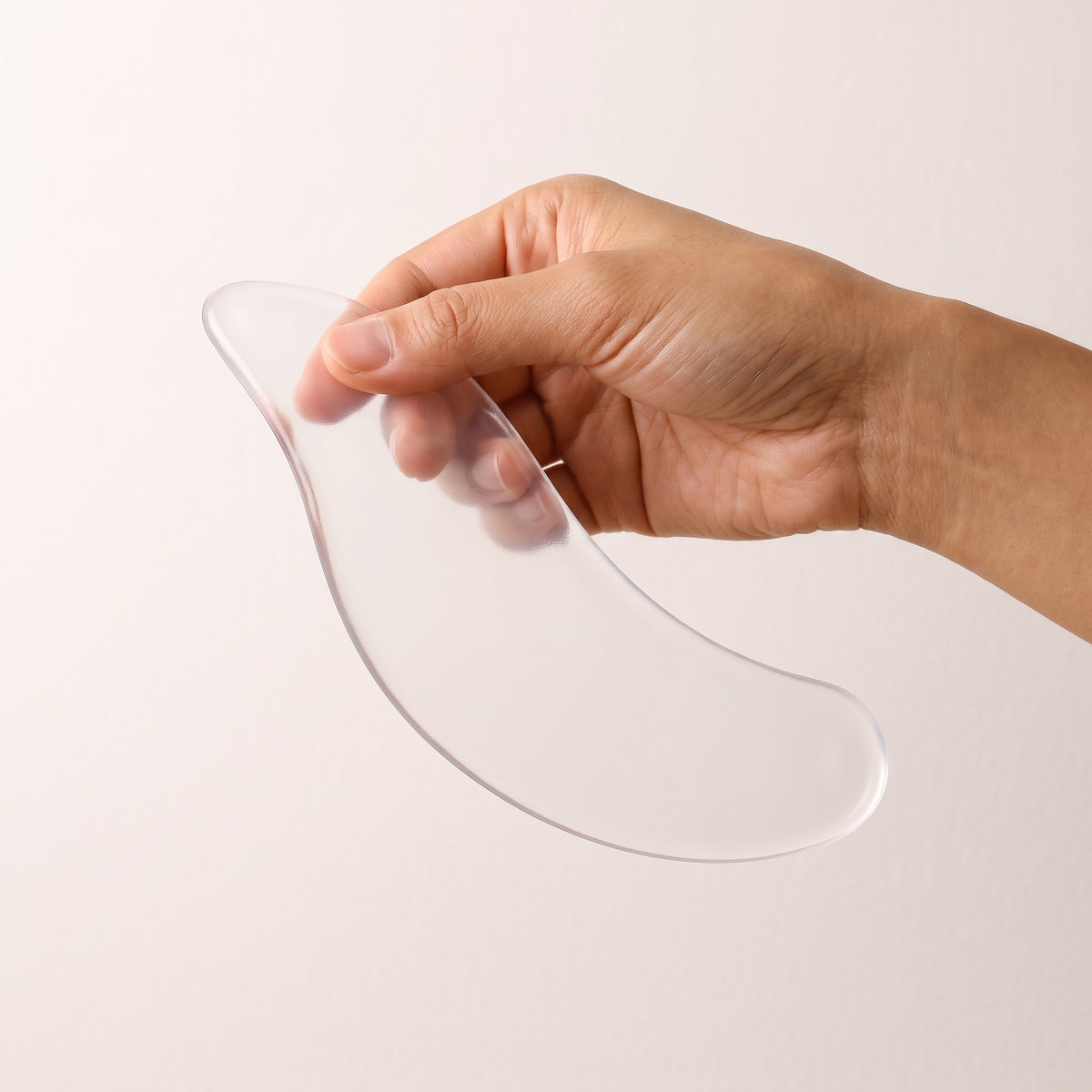 Hand holding the flexible silicone neck patch to show its size
